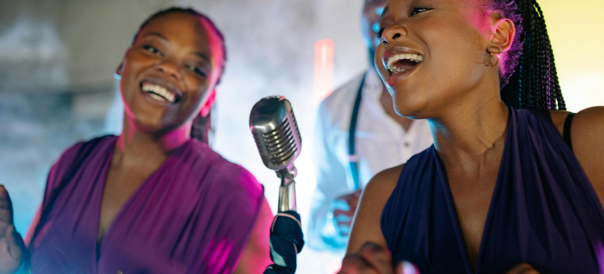 Energetic live performance by African American singers with vintage microphone, vibrant lighting.